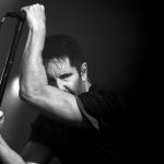 Trent Reznor'u sahnede mikrofon standına yaslanmış halde gösteren siyah beyaz konser fotoğrafı