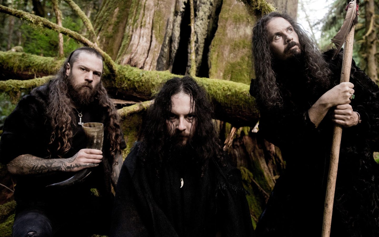 Wolves In The Throne Room'un üç üyesini yosunlu bir ormanda gösteren grup fotoğrafı