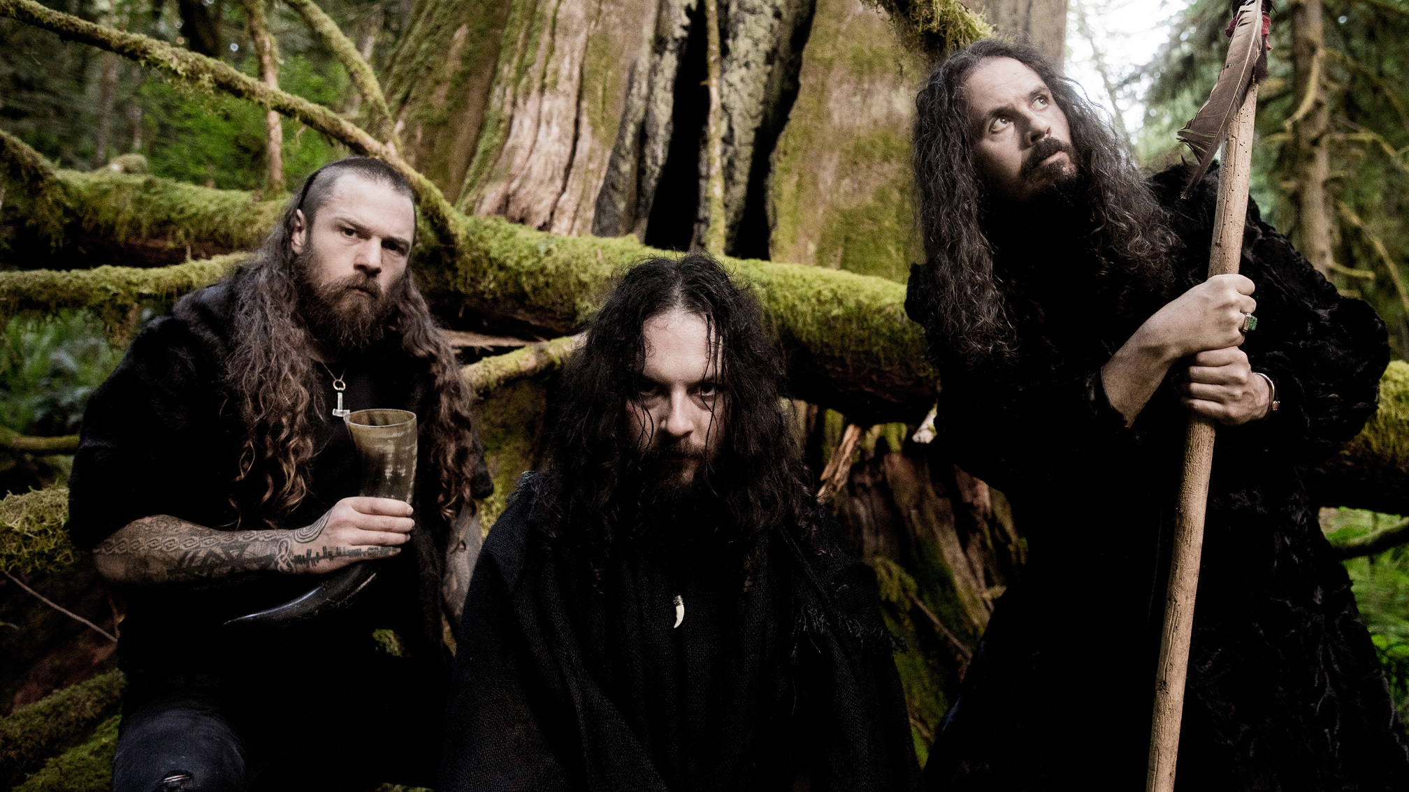 Wolves In The Throne Room'un üç üyesini yosunlu bir ormanda gösteren grup fotoğrafı